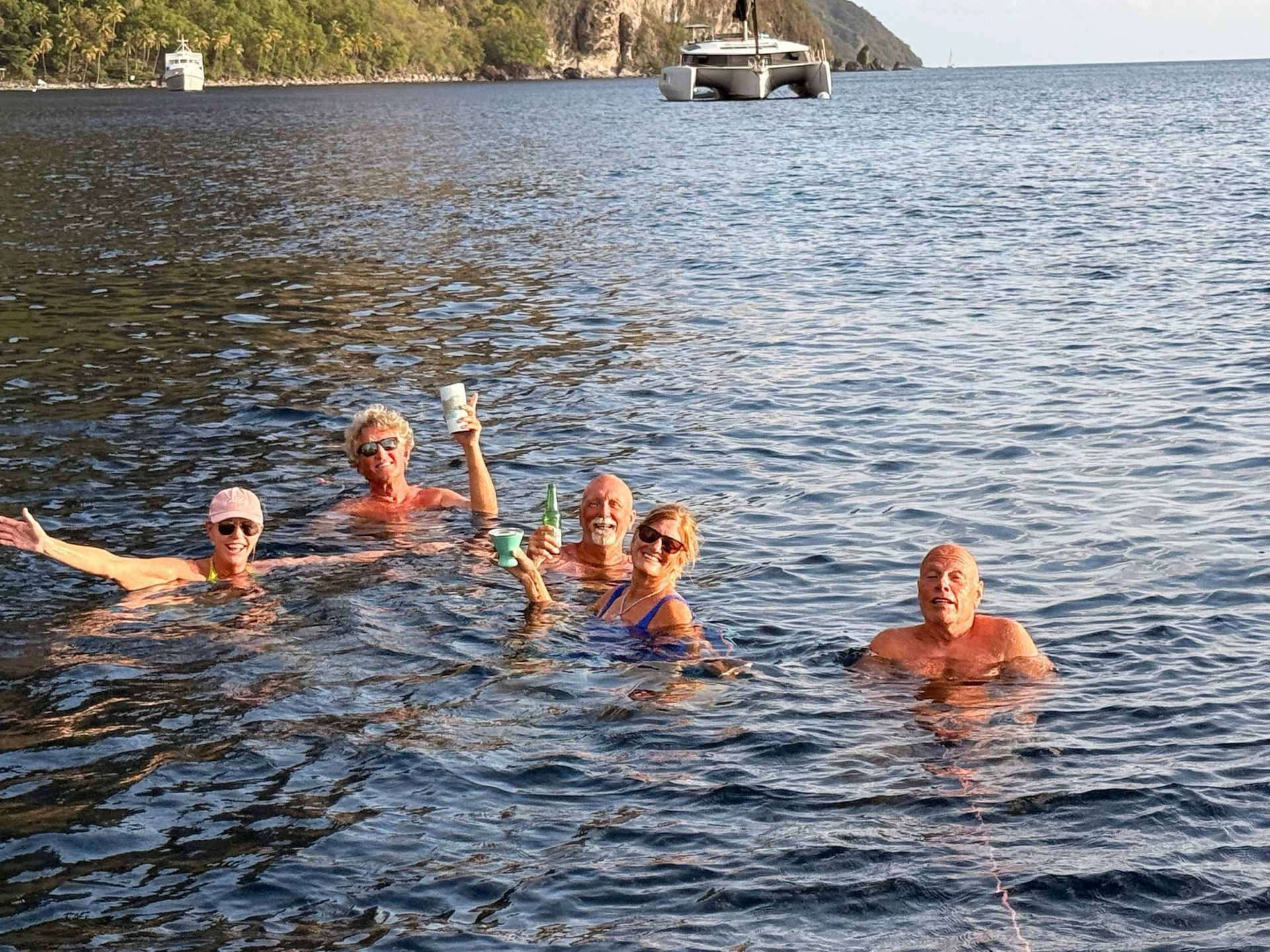 Guests enjoying a swim beside an anchored catamaran